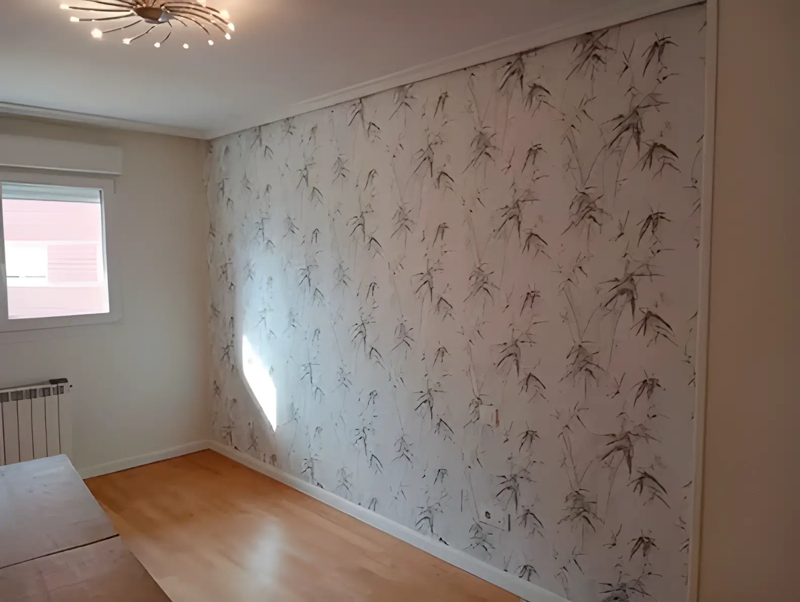 Los Pintores Fuenlabrada colocando papel pintado en pared de acento de habitación luminosa
