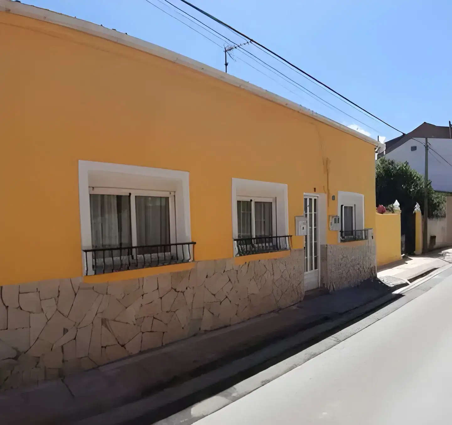 Los Pintores Fuenlabrada Fachada de casa tradicional pintada en color amarillo con zócalo de piedra